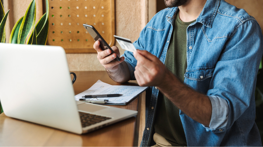 A person holding a credit score offer letter at a desk with a laptop and documents.